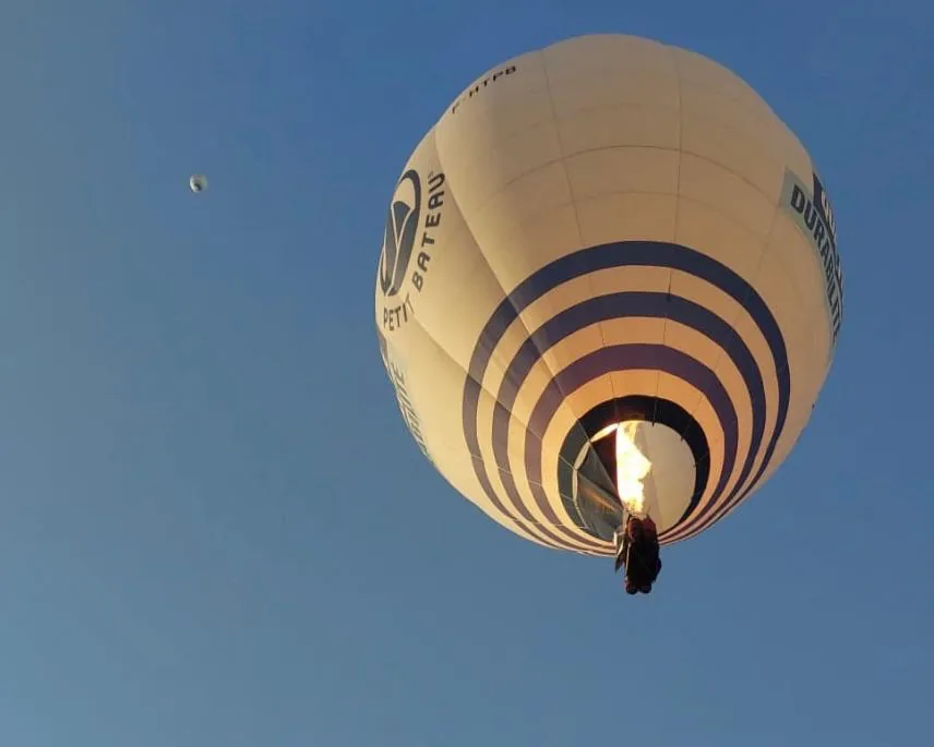 Heißluftballon mit brennendem Brenner am blauen Himmel