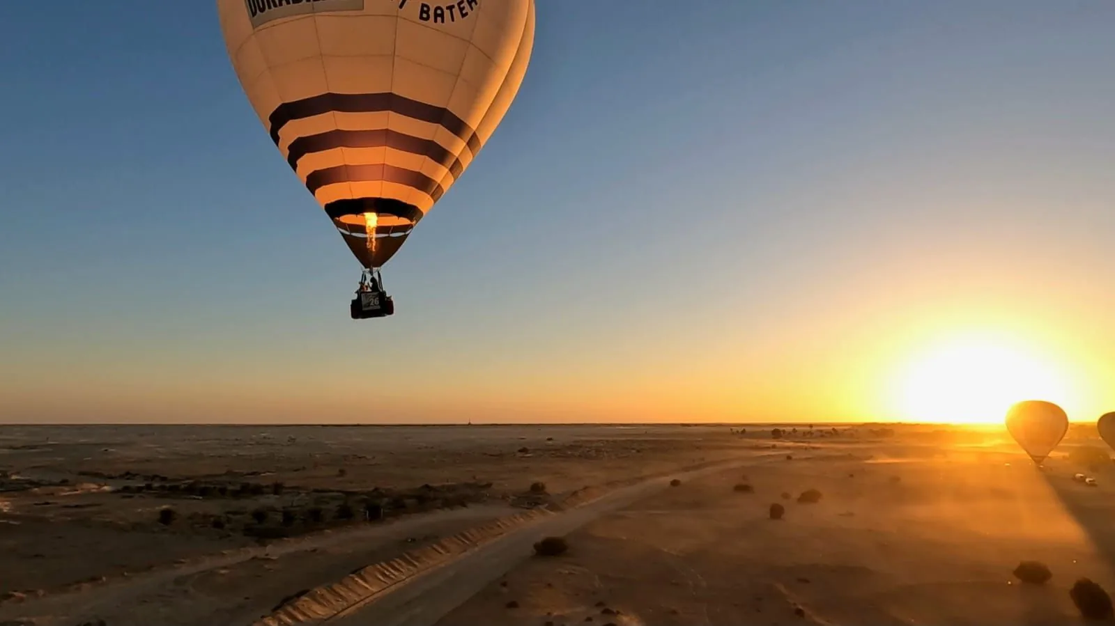 Globo aerostático con el quemador encendido frente al sol naciente