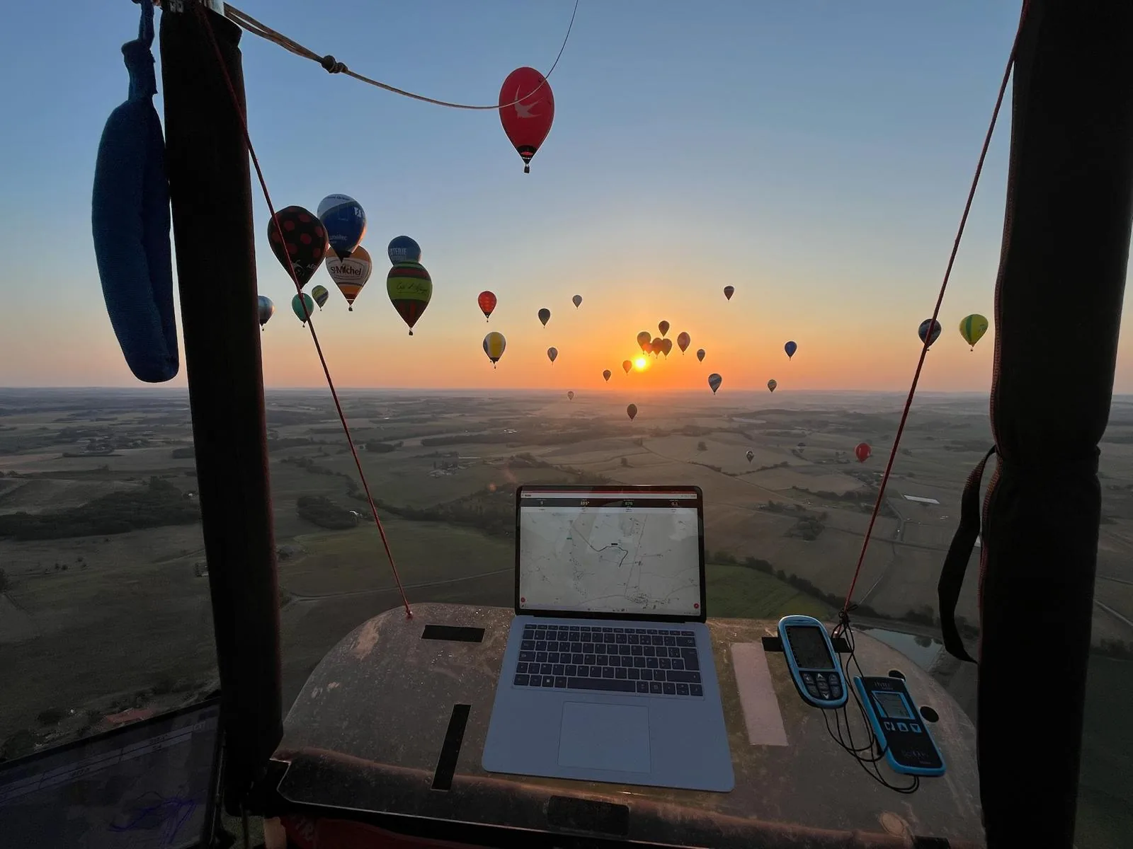 Blick aus dem Korb: WindXplorer auf dem Bildschirm und Dutzende Ballone in der Luft